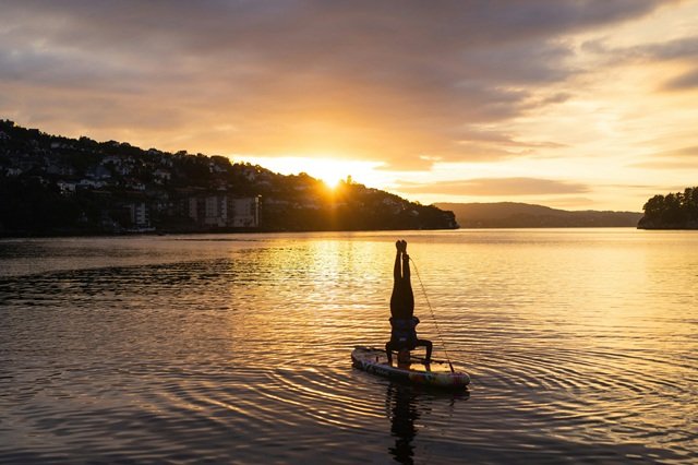 Person standing on their head on a paddle board in Bergen fjord