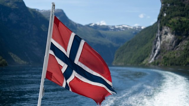Norwegian flag with a fjord in the background